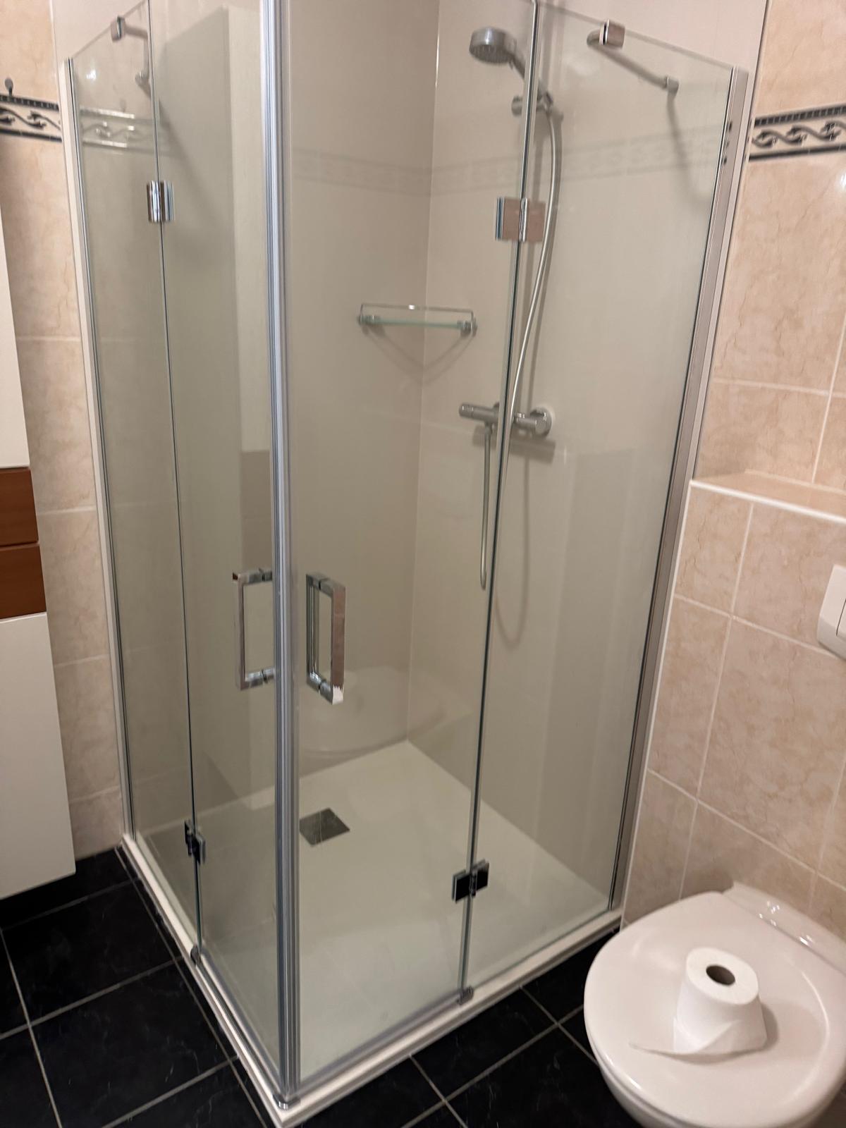 Douchecabine met glazen deur en toilet in moderne badkamer