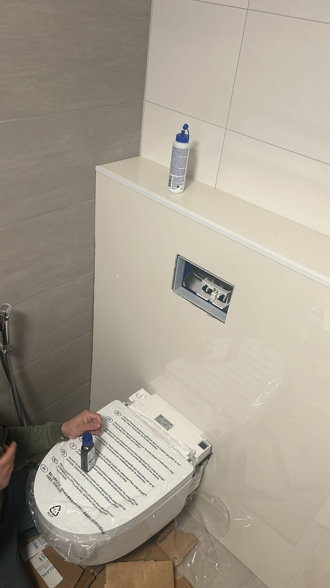 Wit toilet in aanbouw, beige betegeling en verpakte toebehoren