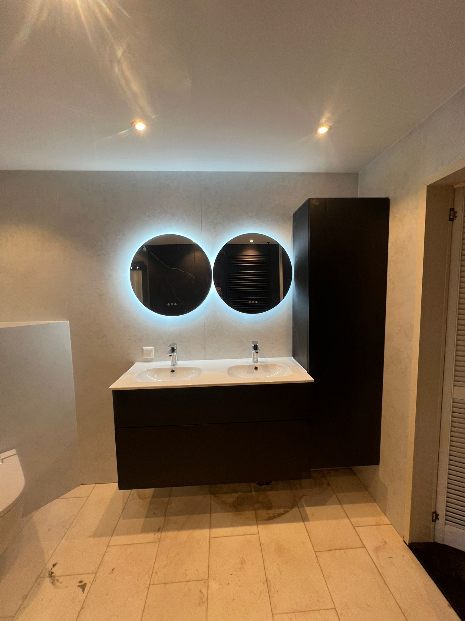 Moderne badkamer met dubbele wastafel en verlichte ronde spiegels