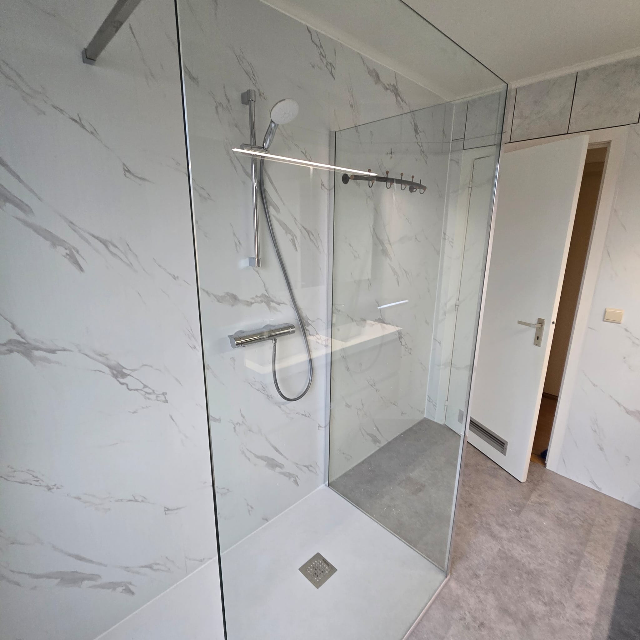 Douchecabine met glazen wand en marmerlook tegels in grijs en wit