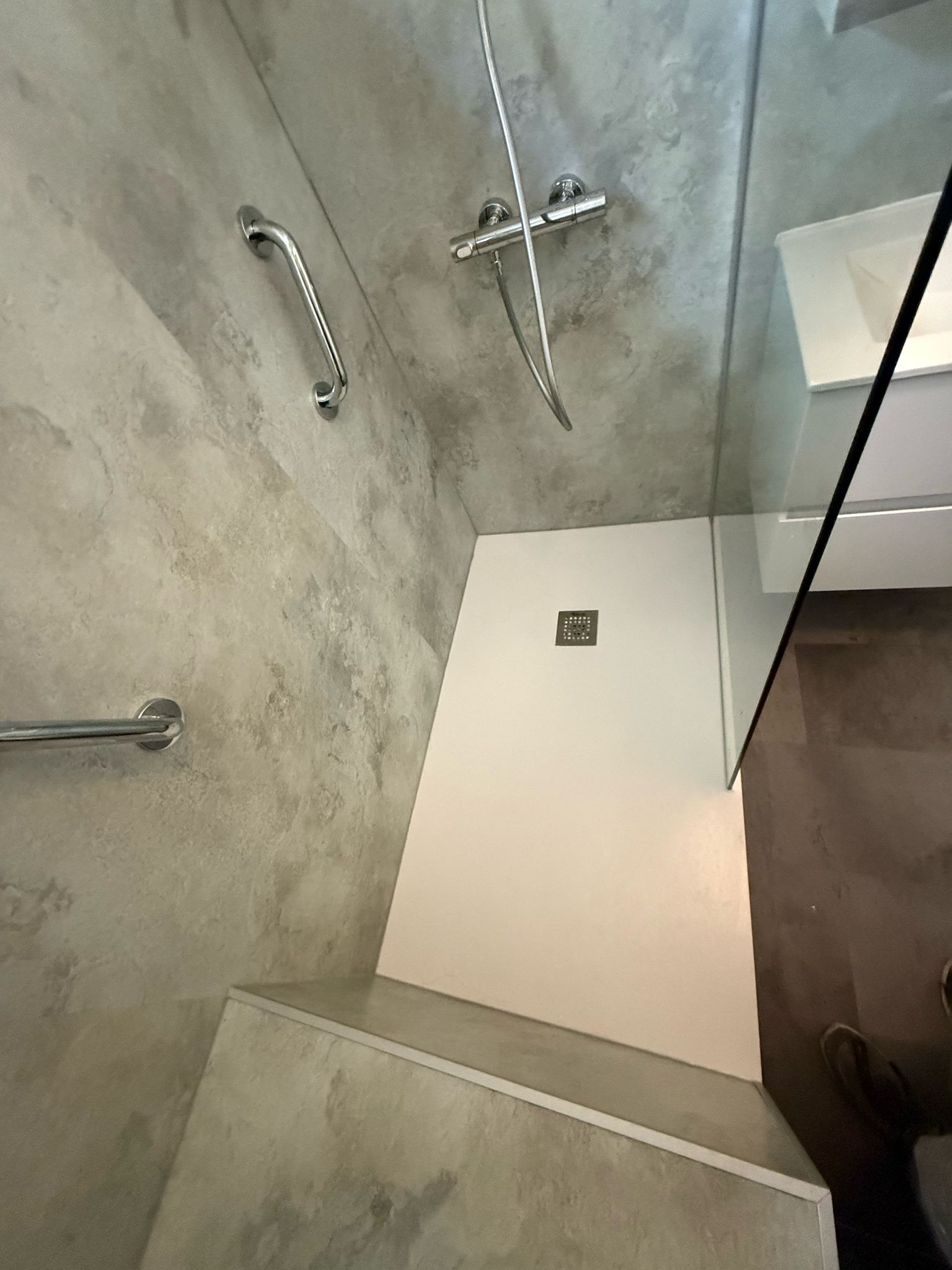 Douche area met grijs betegelde wanden en witte douchebak