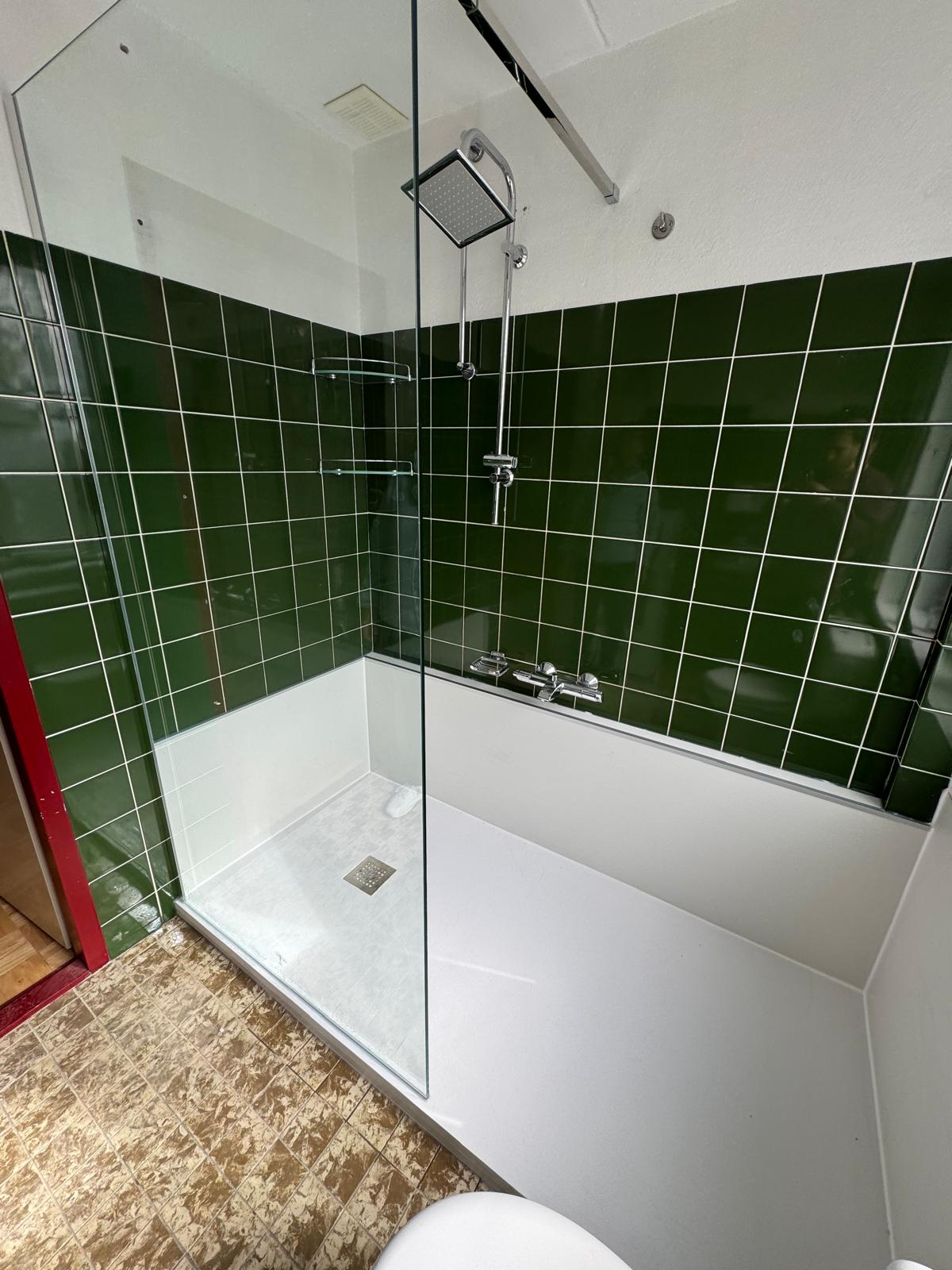 Douchecabine met groene tegels en glazen deur in moderne badkamer