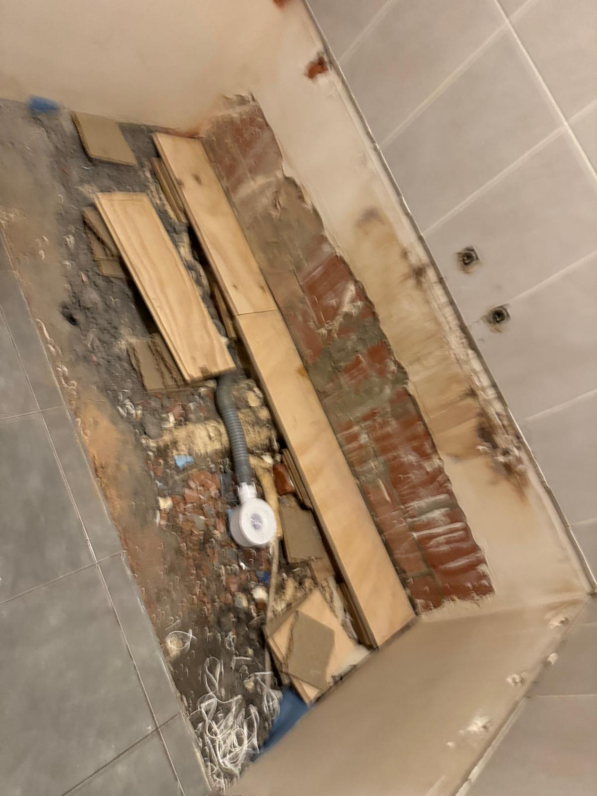 Sloopwerk badkamer, hout en puin op de grond, blootgestelde bakstenen muur