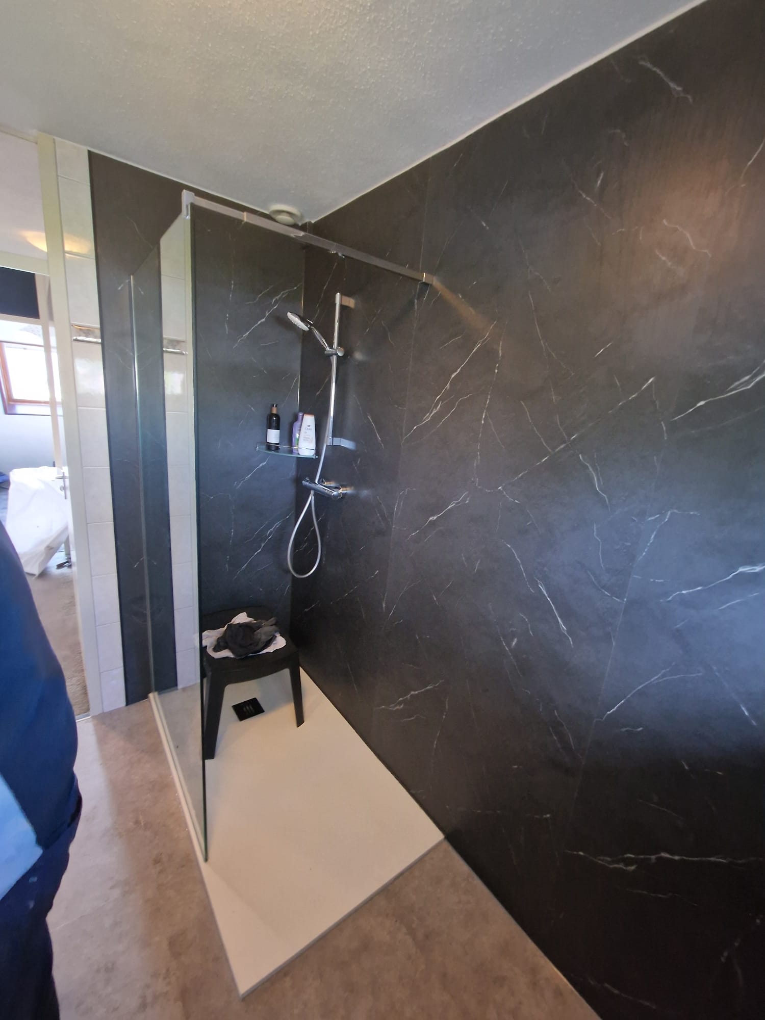 Douchecellen met zwarte marmeren wand en witte betegelde vloer