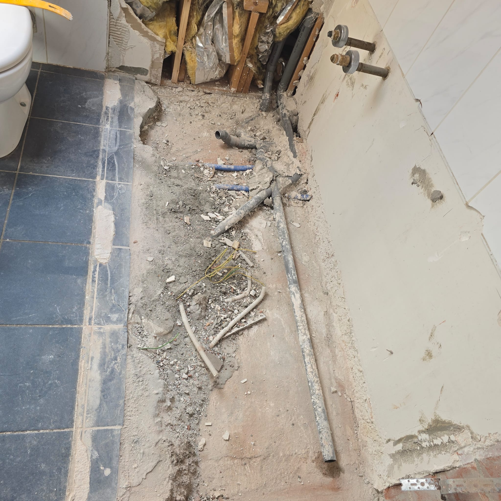 Sloop badkamer vloer met zicht op leidingen en rioleringsbuizen