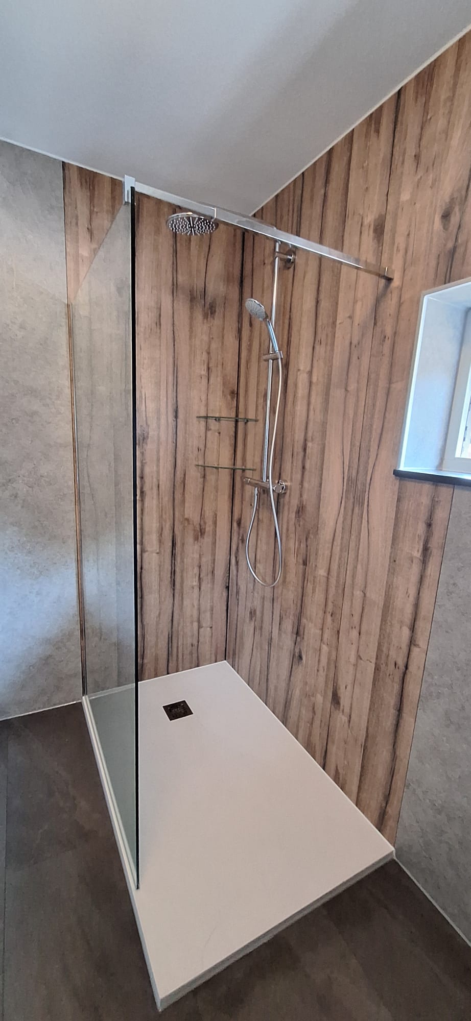 Douchecabine met glazen wand en houten panelen op de wand