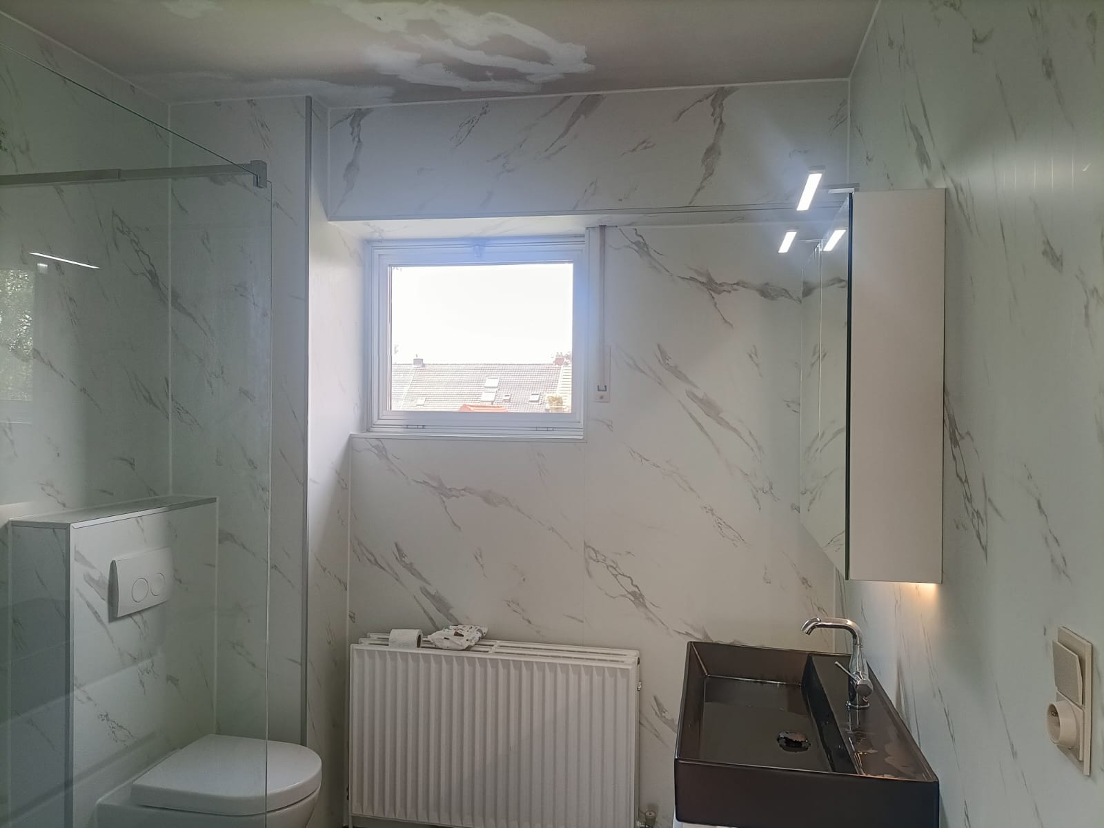 Marmer-look betegelde badkamer met toilet, douche en wasbak