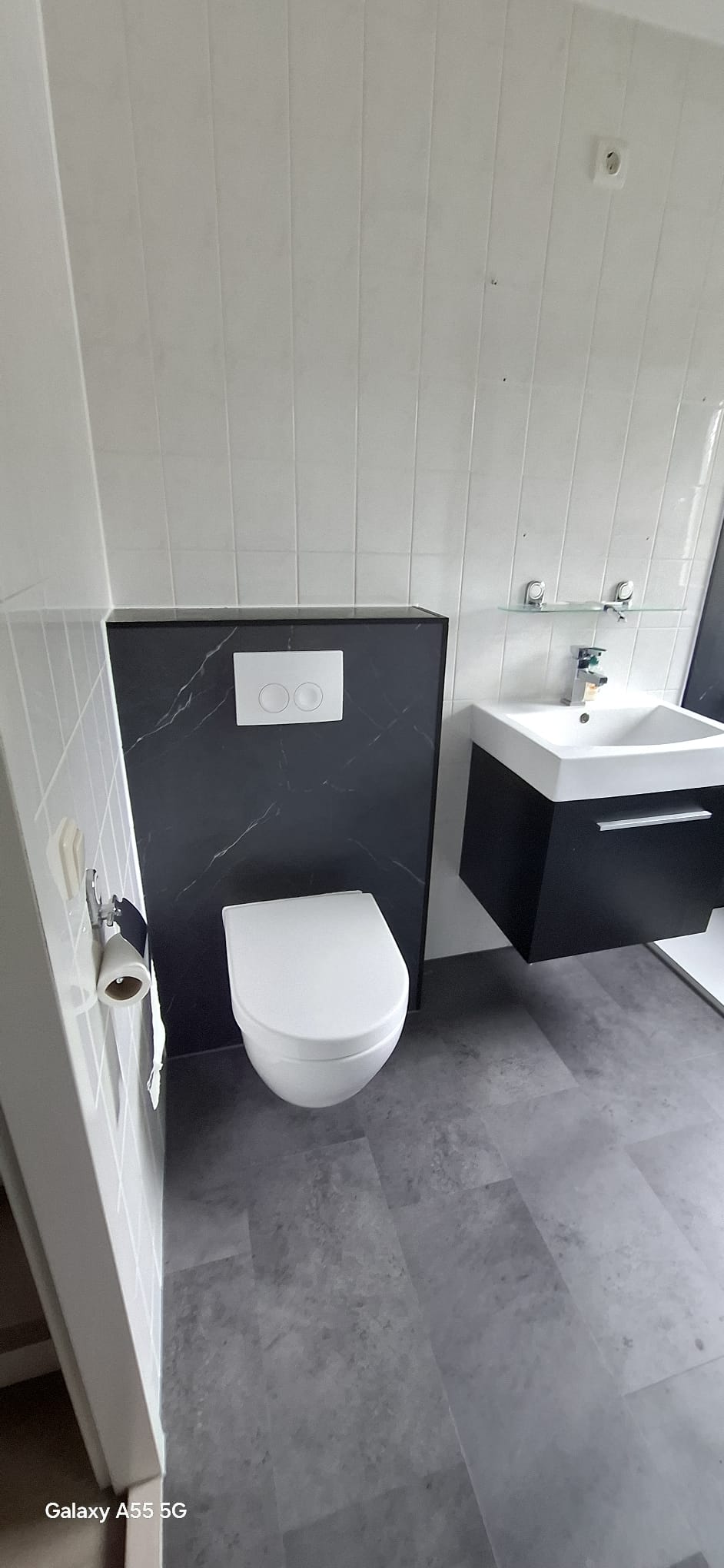 Moderne badkamer met witte toilet en wasbak, zwarte en grijze tegelwerk