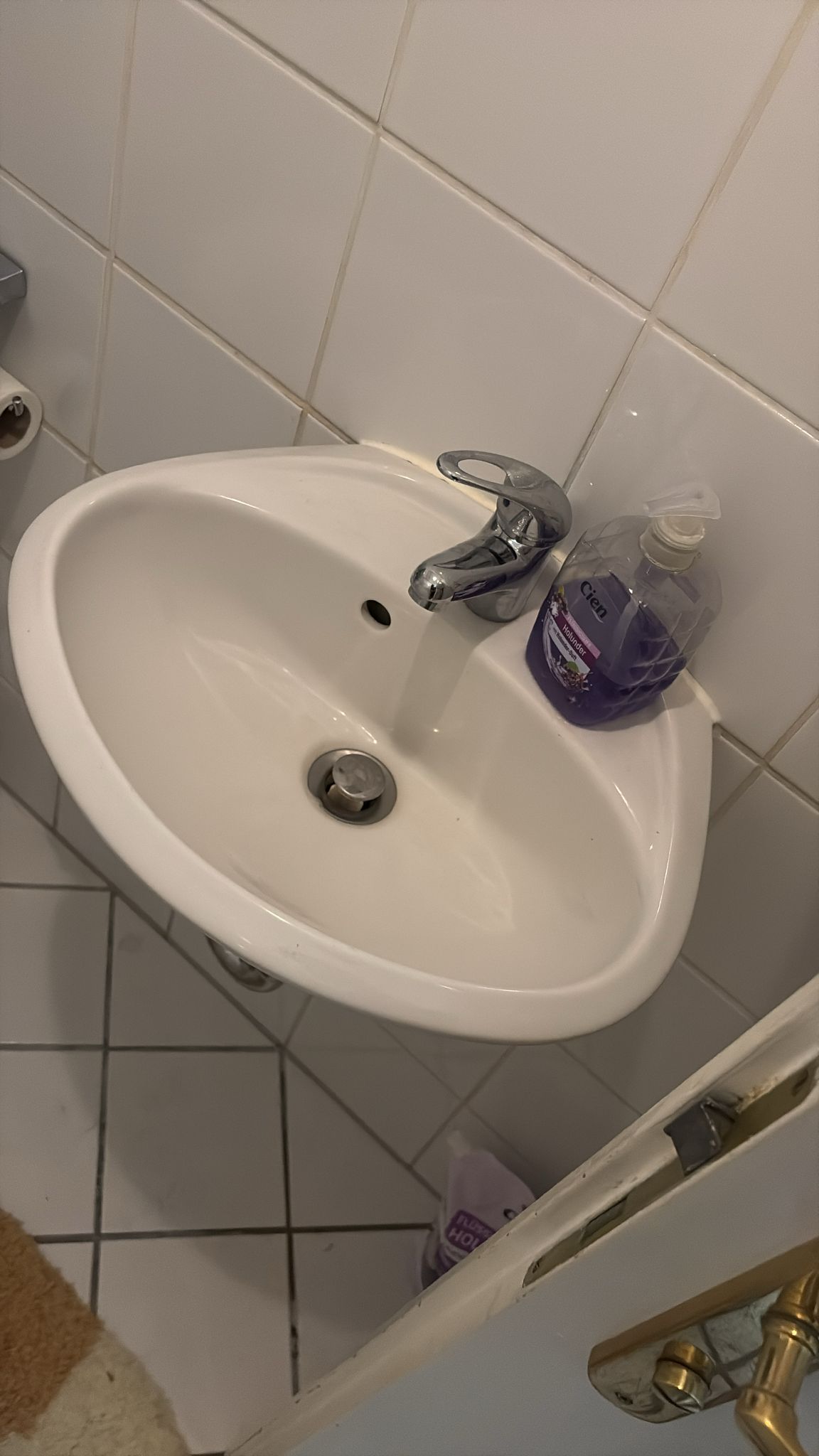 Wit betegelde badkamer met witte wastafel en chroom kraan