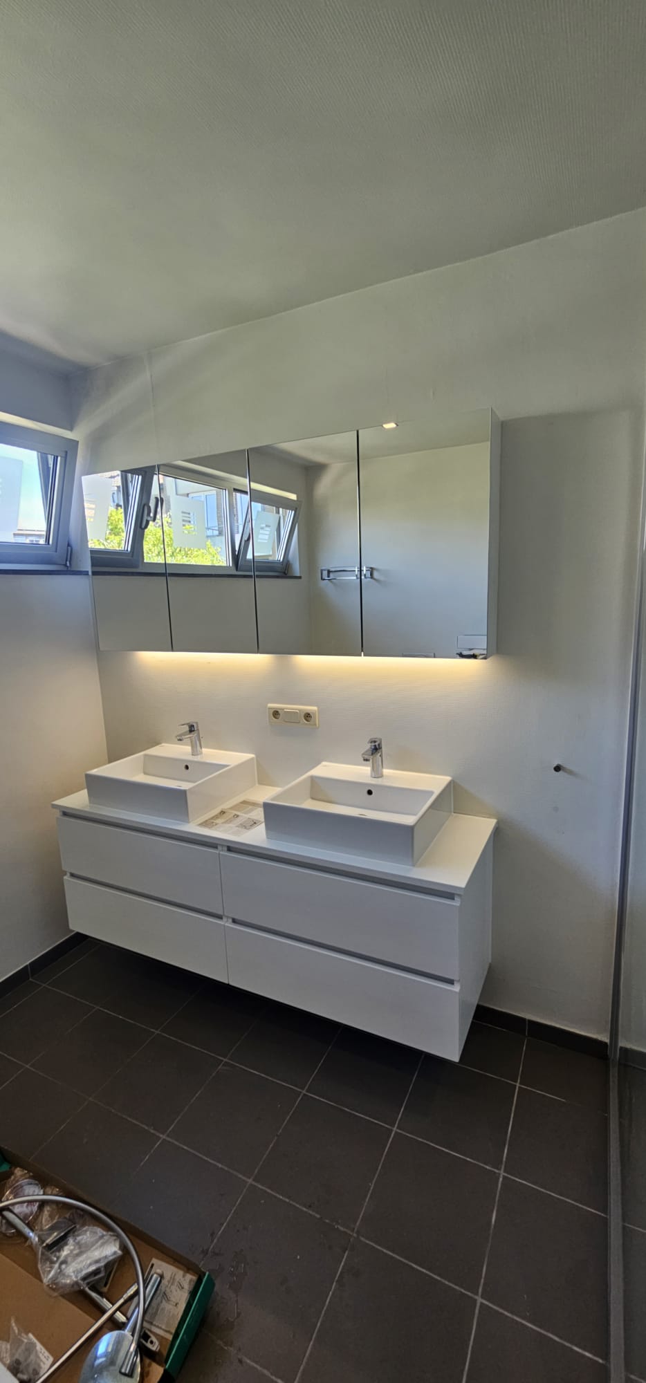 Dubbele wastafel met witte meubels en zwarte tegelvloer in moderne badkamer
