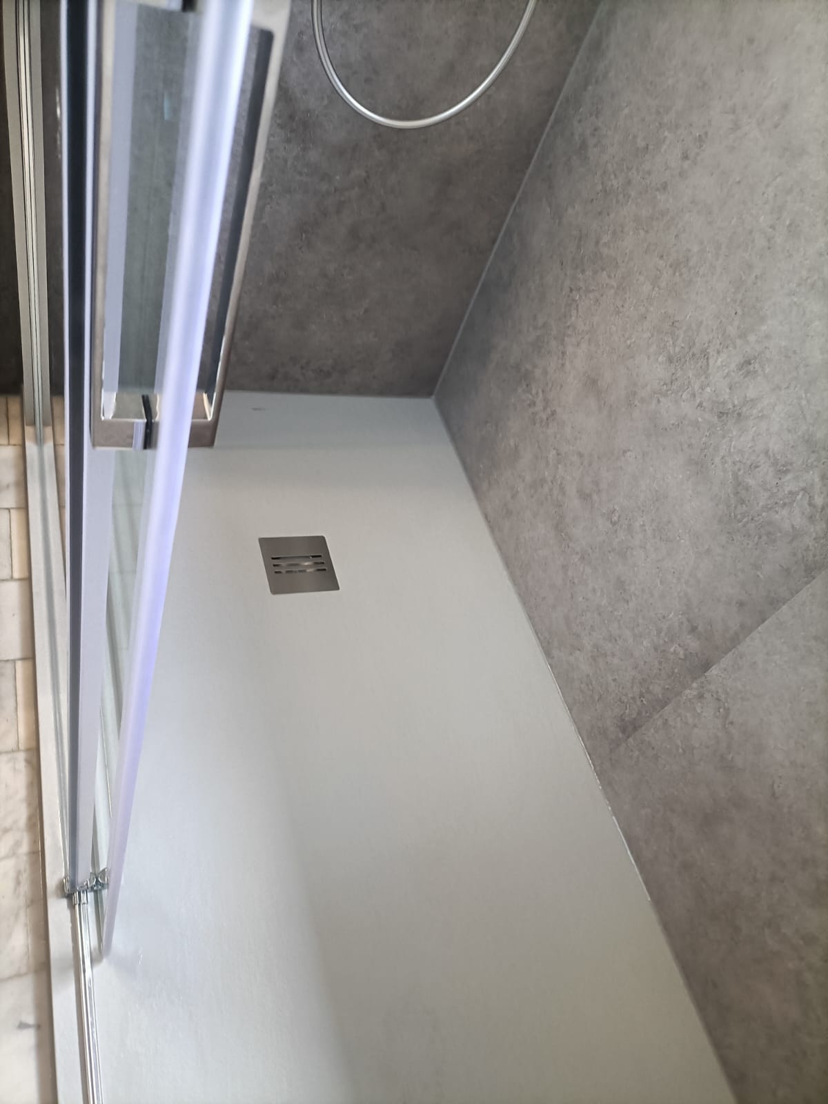 Douche ruimte met grijze wandtegels en witte vloer