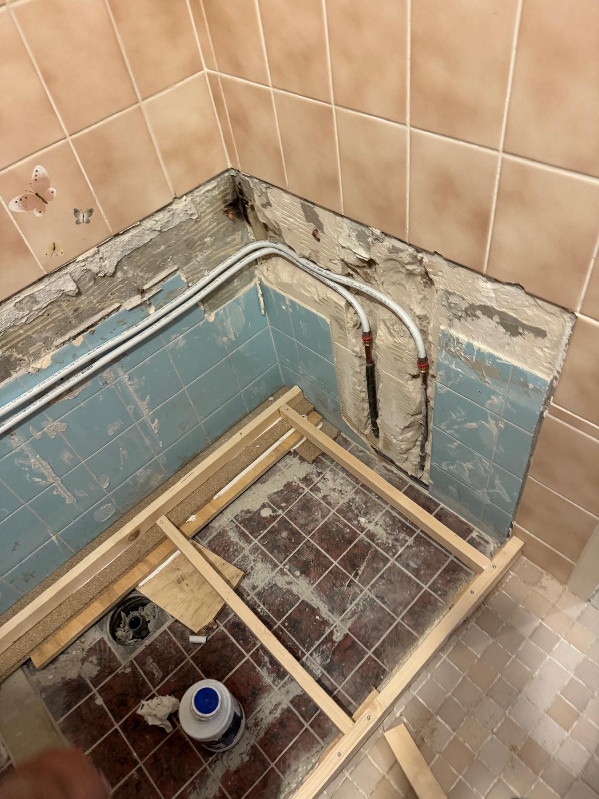 Sloop badkamer met zicht op betegelde muren en vloer met houten frame