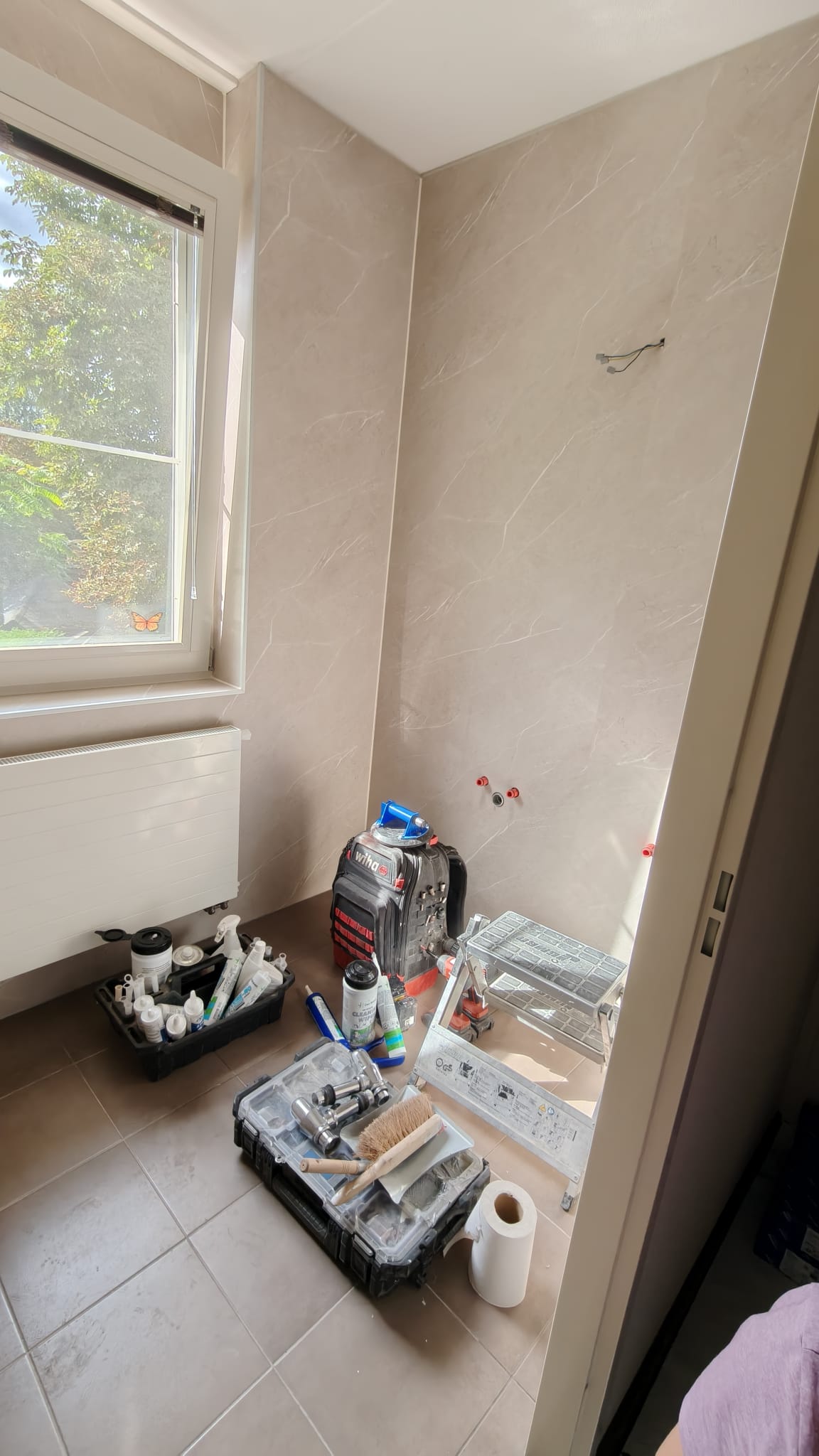 Tijdens badkamer renovatie, beige marmerlook tegels, gereedschap en materialen op de vloer