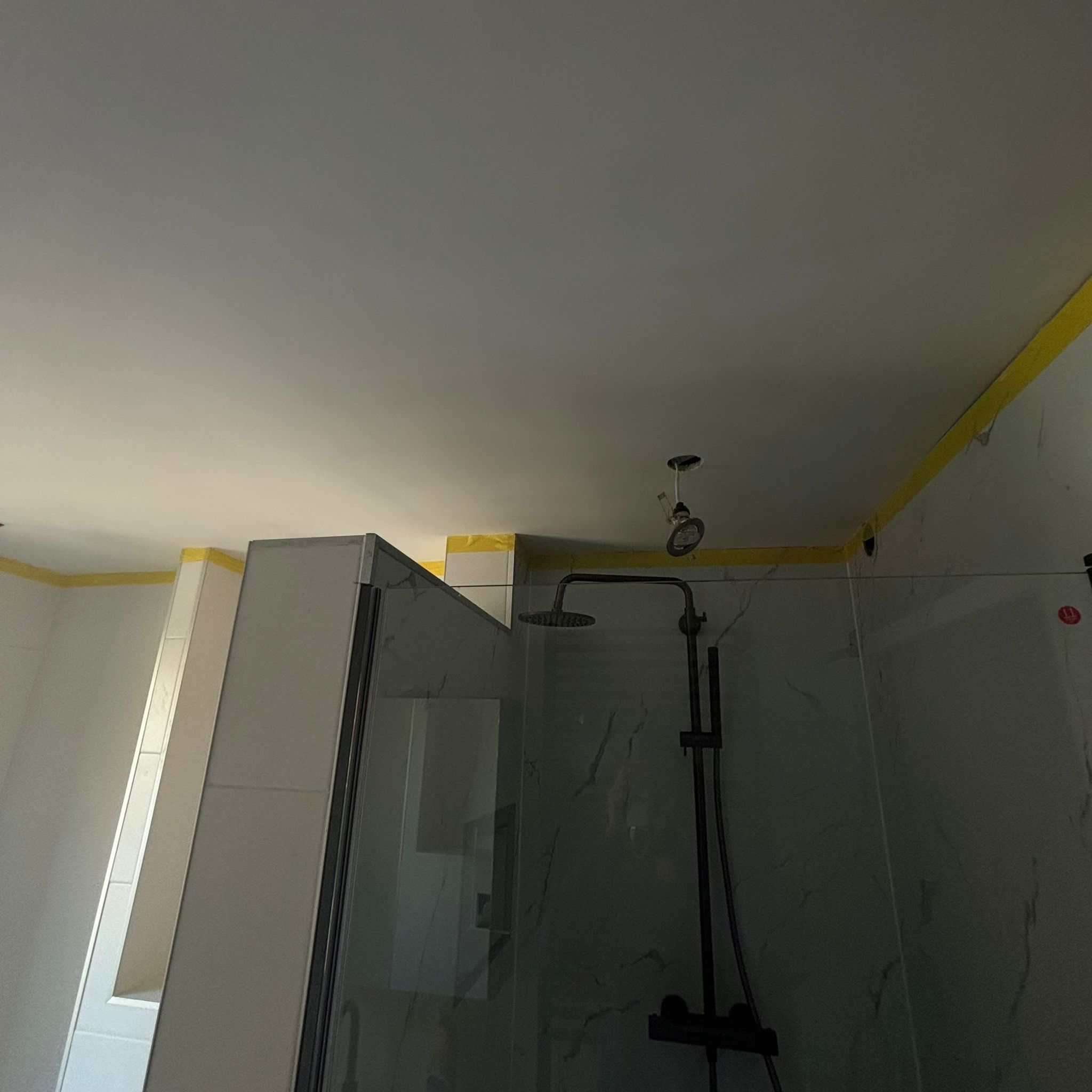Schilderwerk in badkamer, douche met glazen deur en witte marmeren tegels