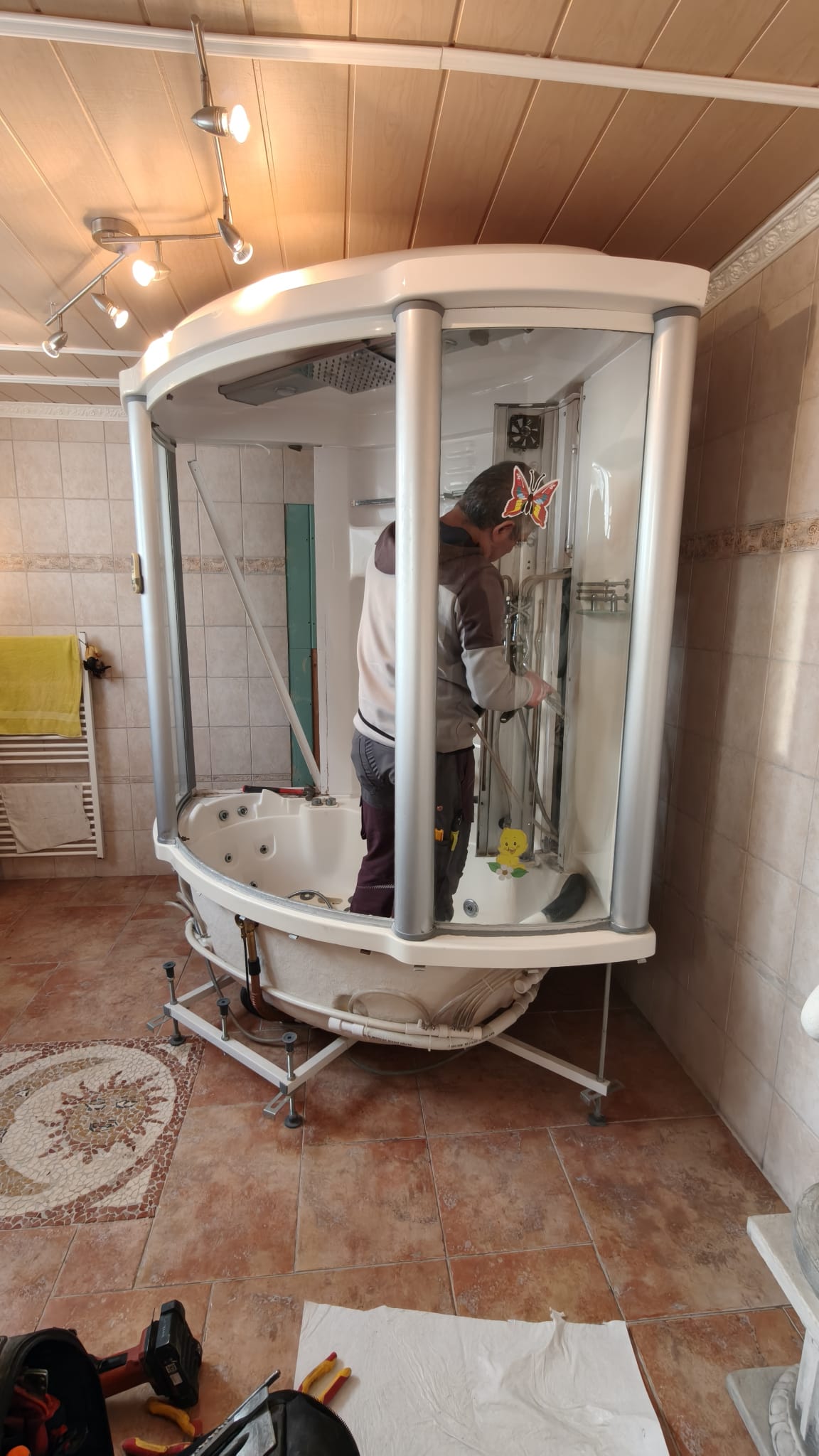 Man installeert witte badkamer douchecabine in betegelde ruimte