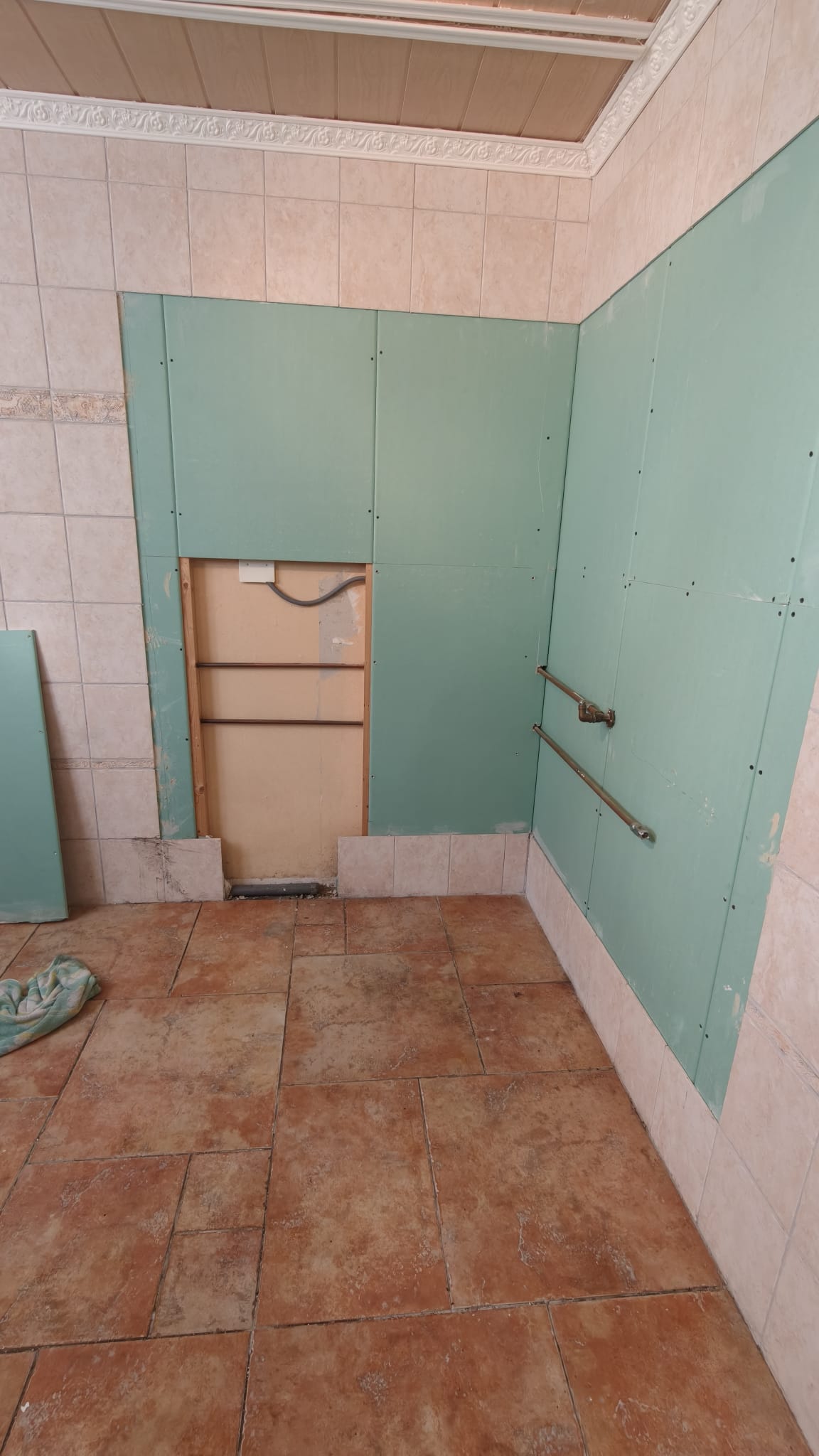 Badkamer tijdens renovatie met groene panelen en betegelde muren en vloer